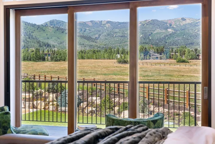 Expansive multi-panel sliding glass door system with wood-finish frames opening to a private balcony featuring a black metal railing