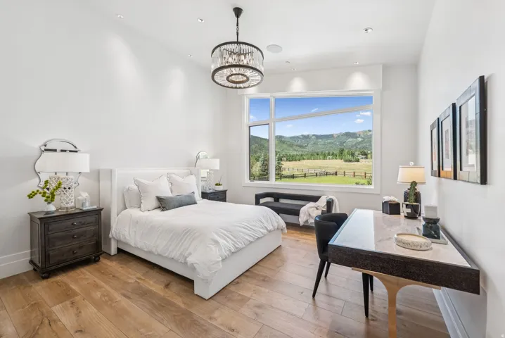 Bright interior space featuring a large picture window, a contemporary chandelier, recessed lighting, and wood-finish flooring