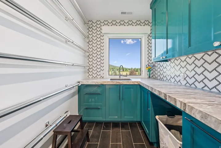 Modern kitchen featuring turquoise cabinetry with sleek hardware, wood-finish countertops, and a geometric tile backsplash in neutral tones