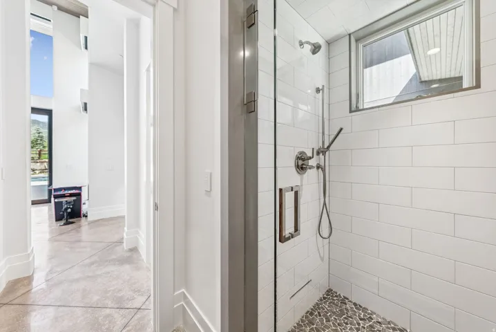 Spa-inspired primary bathroom featuring a frameless glass-enclosed walk-in shower with subway tile surround, pebble floor, and brushed nickel fixtures