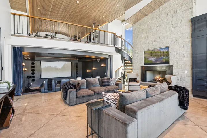 Great room featuring a natural stone fireplace, a spiral staircase, and high ceilings with wood-paneling