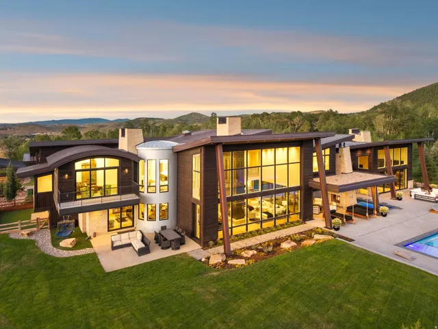 Contemporary architectural design featuring expansive window walls, multiple balconies, a patio, and a swimming pool