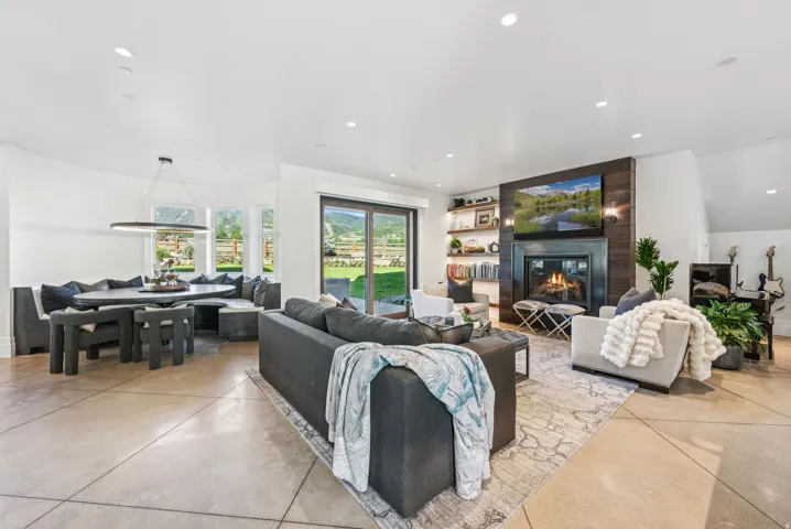 Open-concept living area featuring a fireplace with dark wood paneling, built-in shelving, and large sliding glass doors