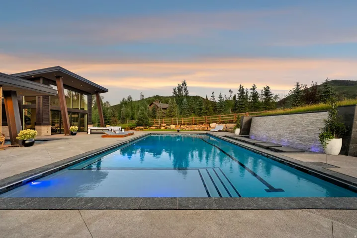 Resort-style saltwater swimming pool featuring lane markings, surrounded by expansive stamped concrete decking