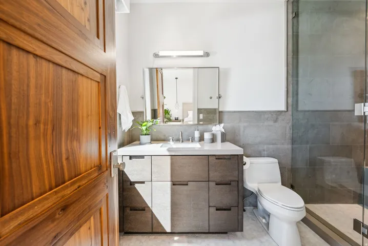 Modern spa-inspired bathroom featuring a floating vanity with dual rectangular vessel sinks, light wood-finish cabinetry with ample storage, and a quartz countertop