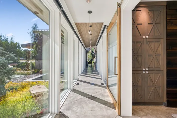 Expansive window-lined hallway featuring concrete flooring and a wood-paneled ceiling