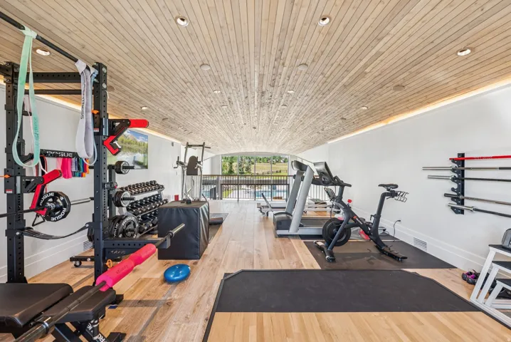 Spacious fitness area featuring a vaulted wood-finish ceiling with recessed lighting, wood-finish flooring, and white wall finishes