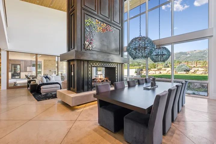 Spacious interior featuring a large fireplace with decorative metalwork, soaring ceilings with wood paneling, and polished concrete flooring