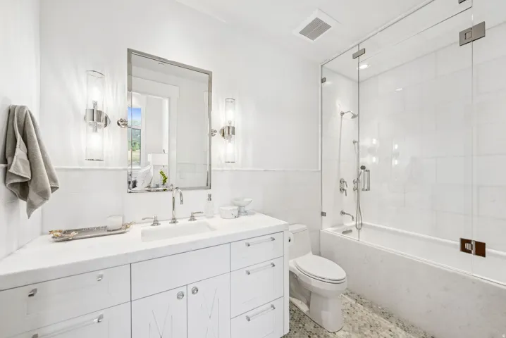 White bathroom featuring a vanity with an integrated sink, polished chrome fixtures, and a framed mirror