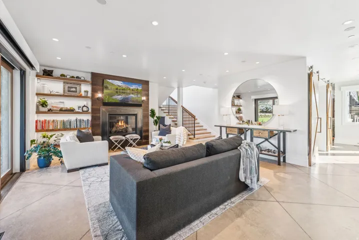 Spacious living area featuring a fireplace with a wood-paneled accent wall, built-in shelving, concrete-finish flooring, and sliding barn doors