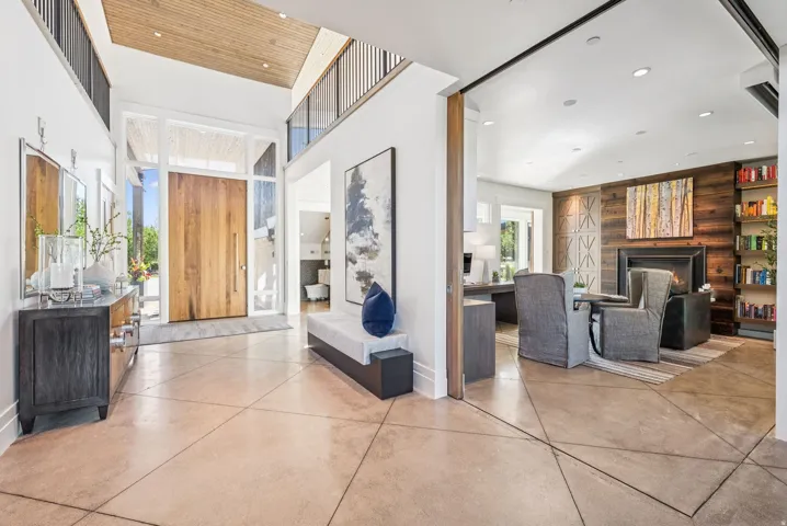 Grand double-height entry with a natural wood door and transom windows