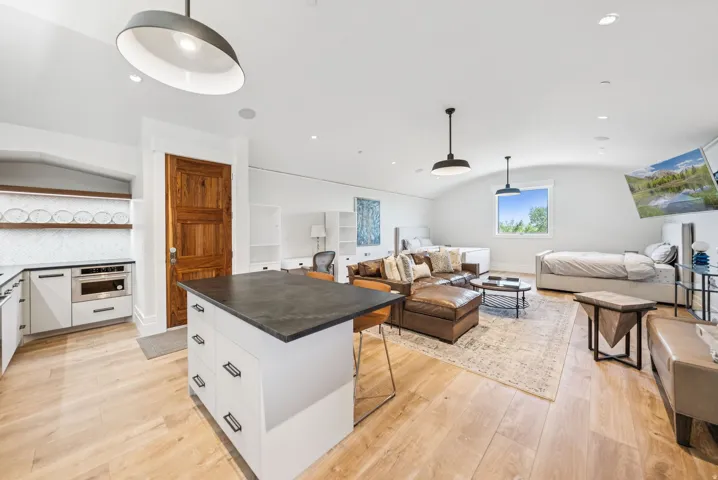 Open-concept living space featuring wide plank wood-finish flooring and a vaulted ceiling