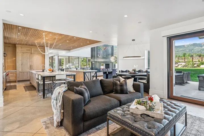 Spacious open-concept interior featuring light wood cabinetry, a large kitchen island with seating, recessed lighting, and a wood-panel accent ceiling