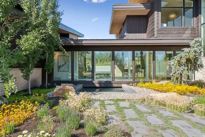 Modern architectural exterior with extensive glass paneling, dark wood-finish siding, and stone accents