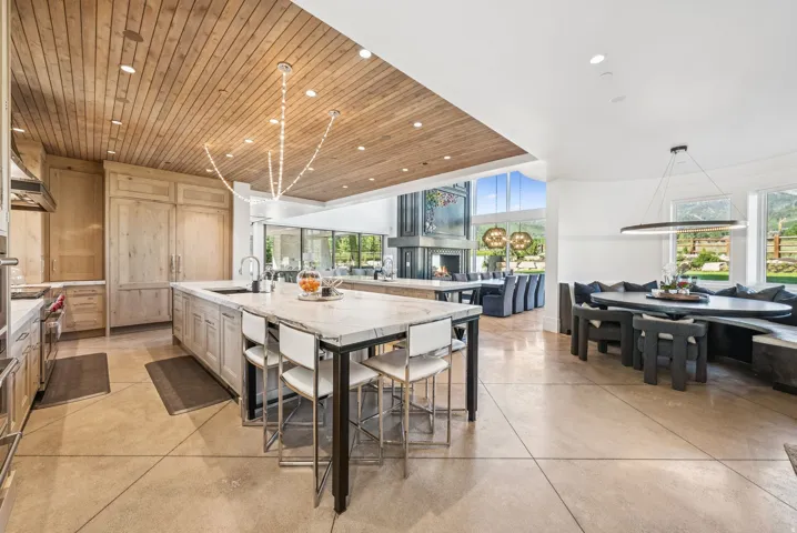 Gourmet kitchen featuring a substantial central island with seating, a large integrated refrigeration unit, professional-grade appliances, and a wood-paneled ceiling