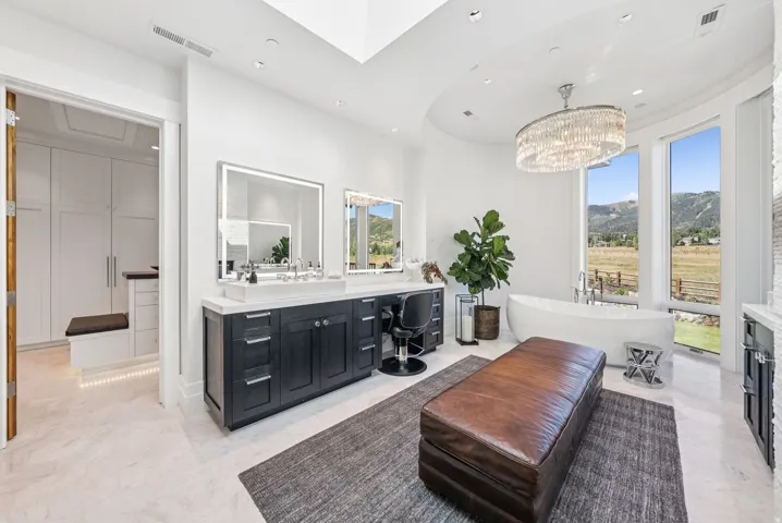 Freestanding soaking tub with panoramic window framing a mountain and field landscape
