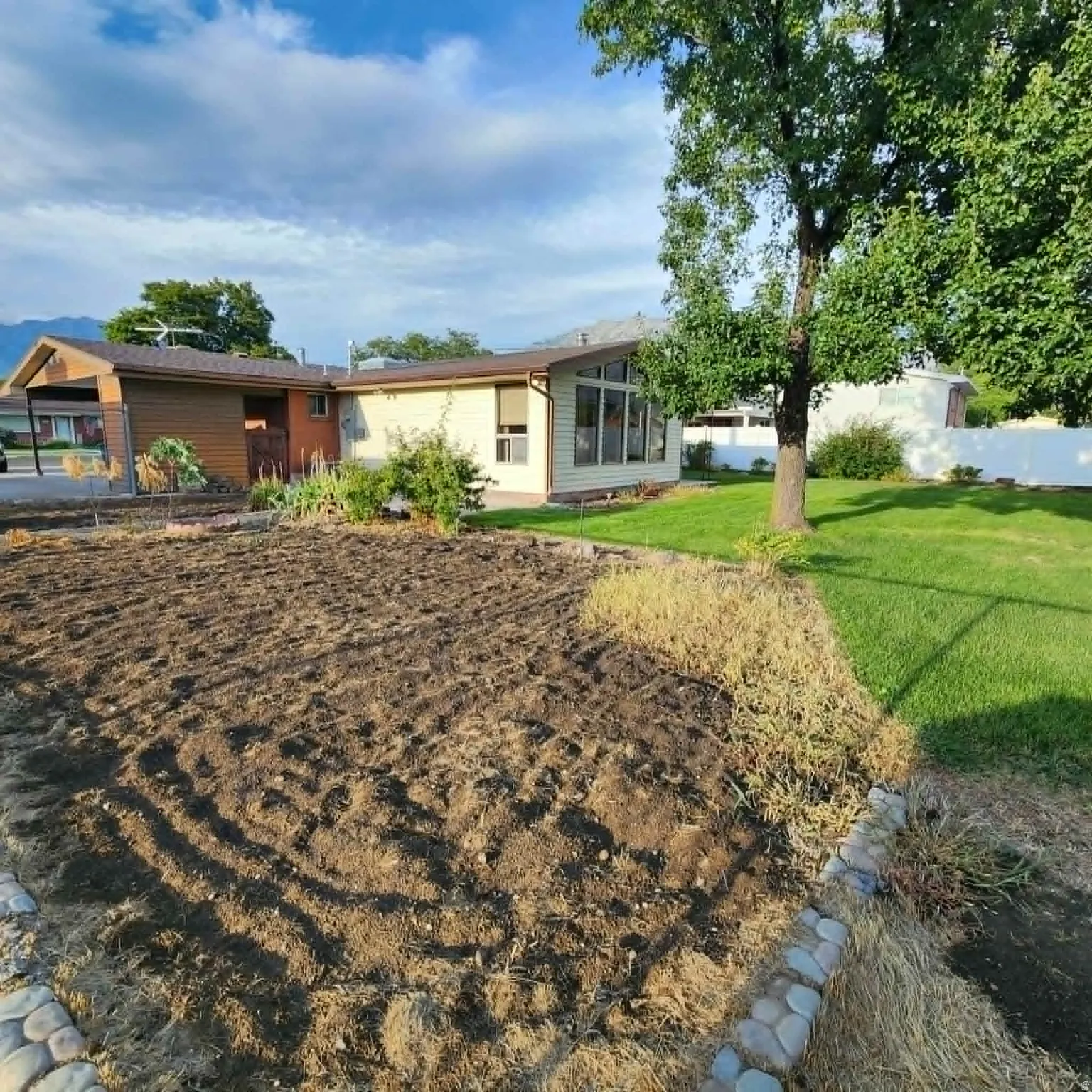 Expansive cultivated garden area with stone border, complemented by a manicured lawn and mature trees