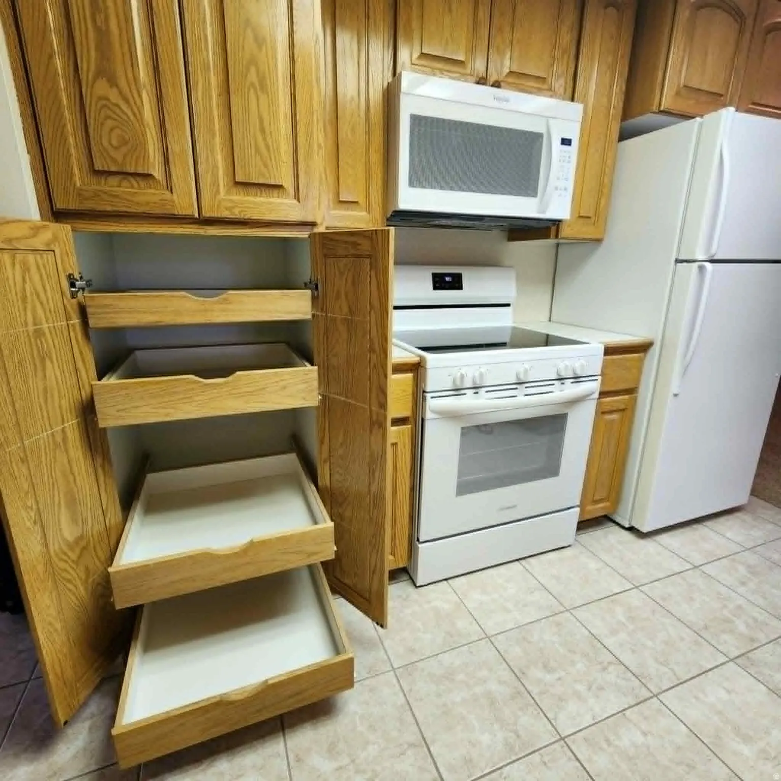 Kitchen featuring wood-finish cabinetry, tile flooring, white electric range, and a white microwave oven