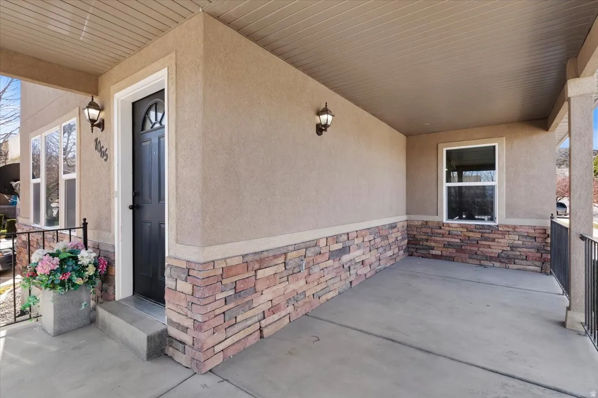 Covered front porch featuring stucco and stone veneer siding