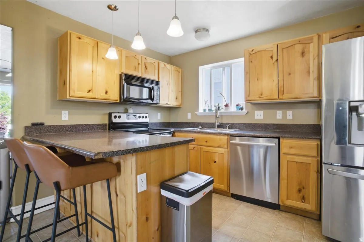 Kitchen featuring wood cabinetry, stainless steel appliances, a kitchen island with seating, and tile flooring