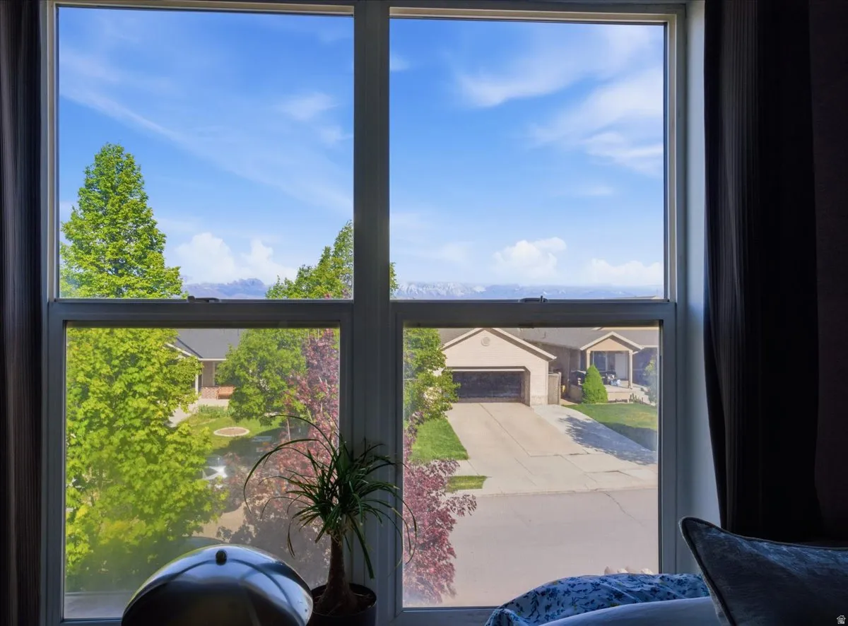 Expansive window offering a broad outlook, featuring a neighborhood setting with mature trees and distant mountains