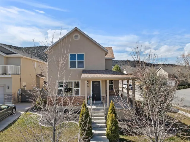 Two-story stucco exterior with a covered front porch, stone accents, and a gabled roof