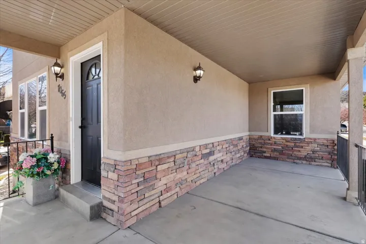 Covered front porch featuring stucco and stone veneer siding