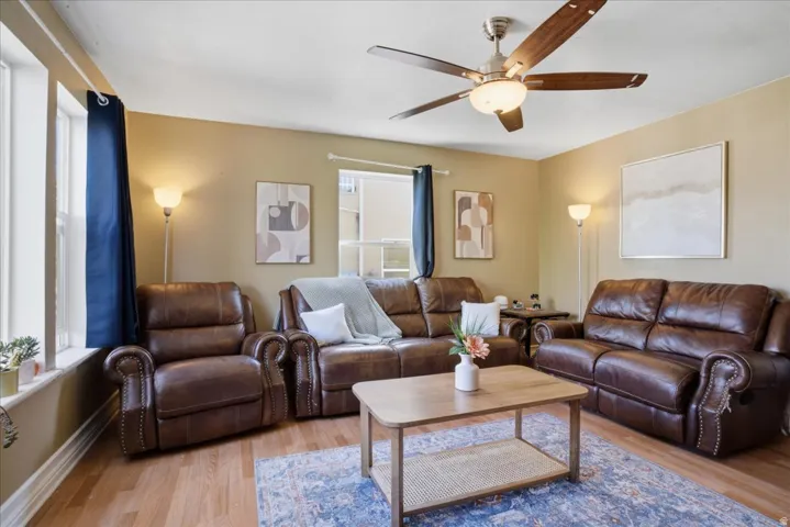 Wood-finish flooring throughout, ceiling fan with integrated lighting, and multiple windows providing natural illumination