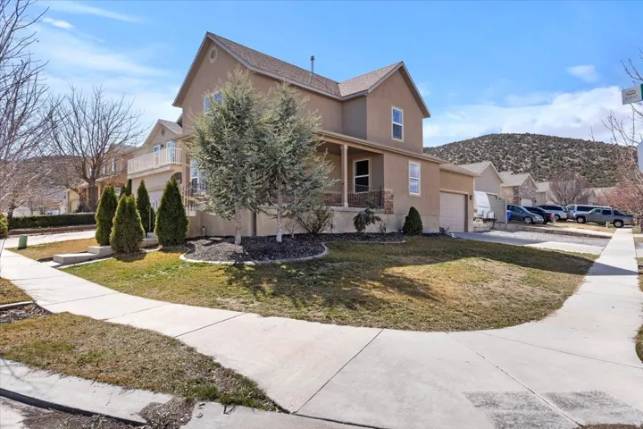 Stucco exterior with a covered porch, an attached garage, landscaped front yard, and concrete sidewalks