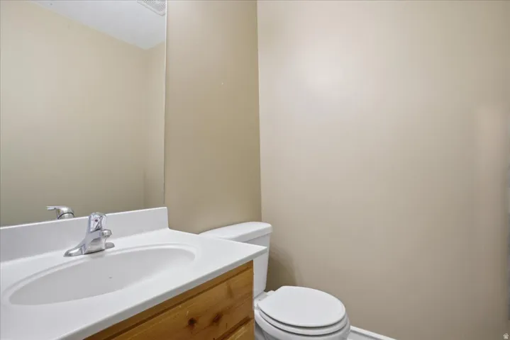 Bathroom featuring a white vanity with integrated sink, chrome faucet, wood-finish cabinetry, and a toilet