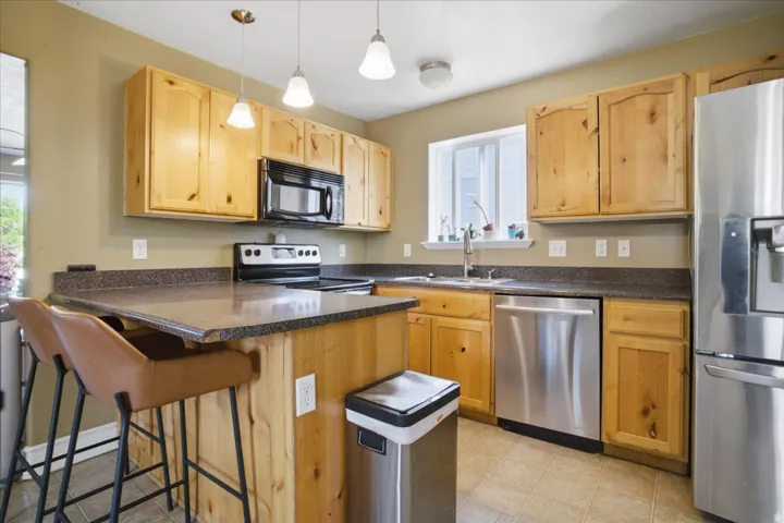 Kitchen featuring wood cabinetry, stainless steel appliances, a kitchen island with seating, and tile flooring
