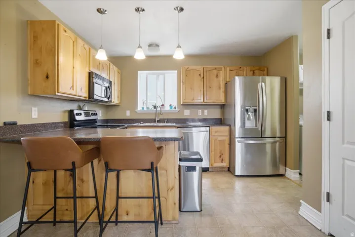 Kitchen featuring stainless steel appliances, wood-finish cabinetry, a breakfast bar, recessed lighting, and a window with natural light