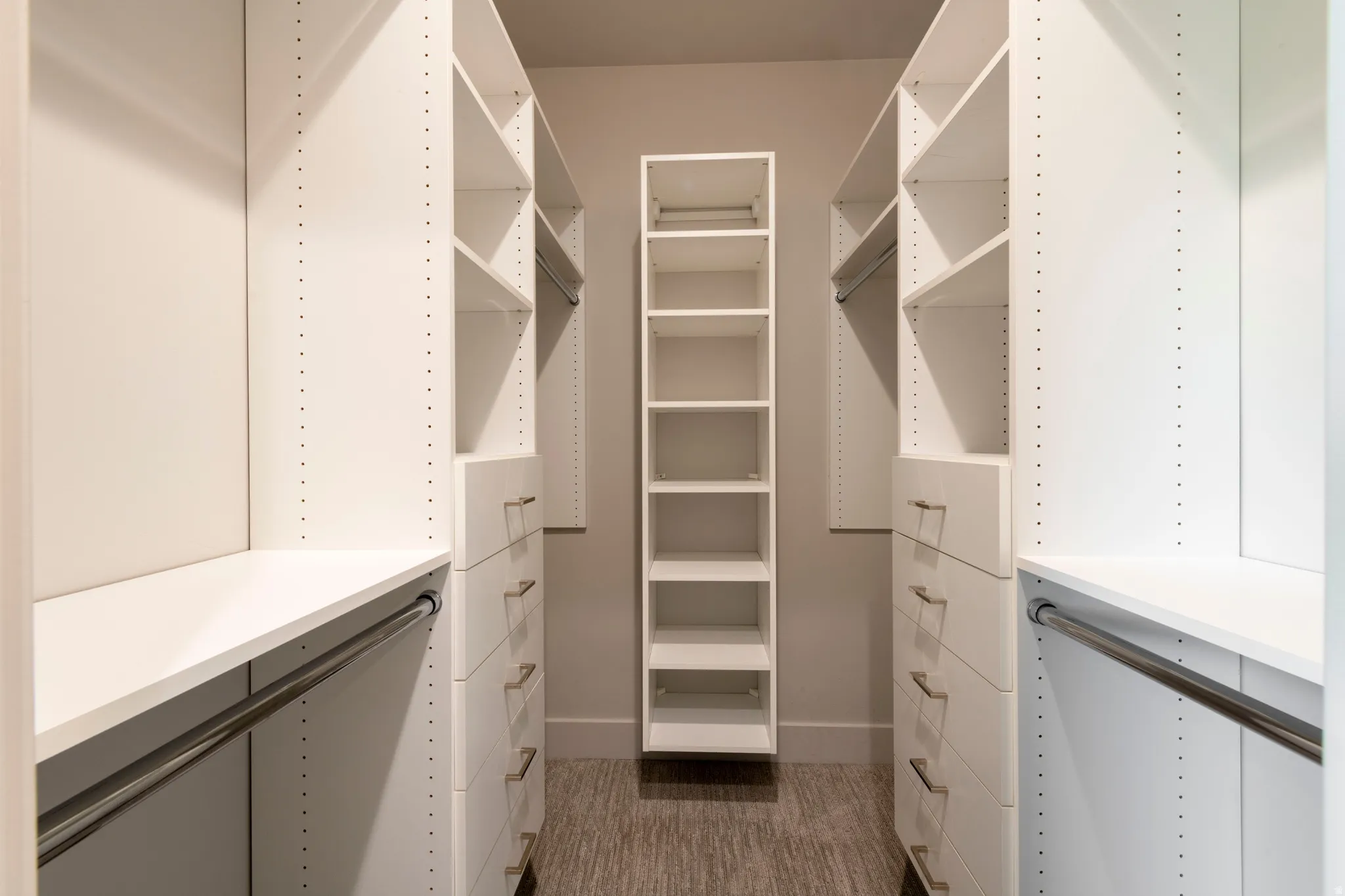 White built-in closet system featuring shelving, drawers with silver-tone hardware, and hanging rods