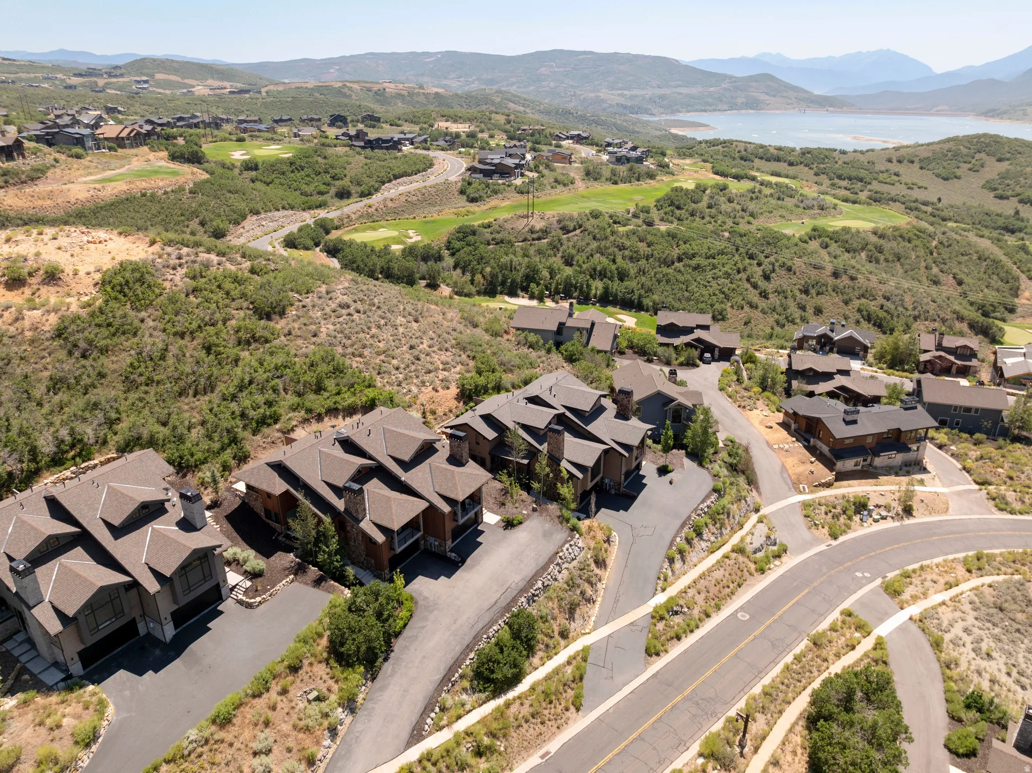 Scattered residential community with natural landscaping, paved roads, and a prominent distant lake