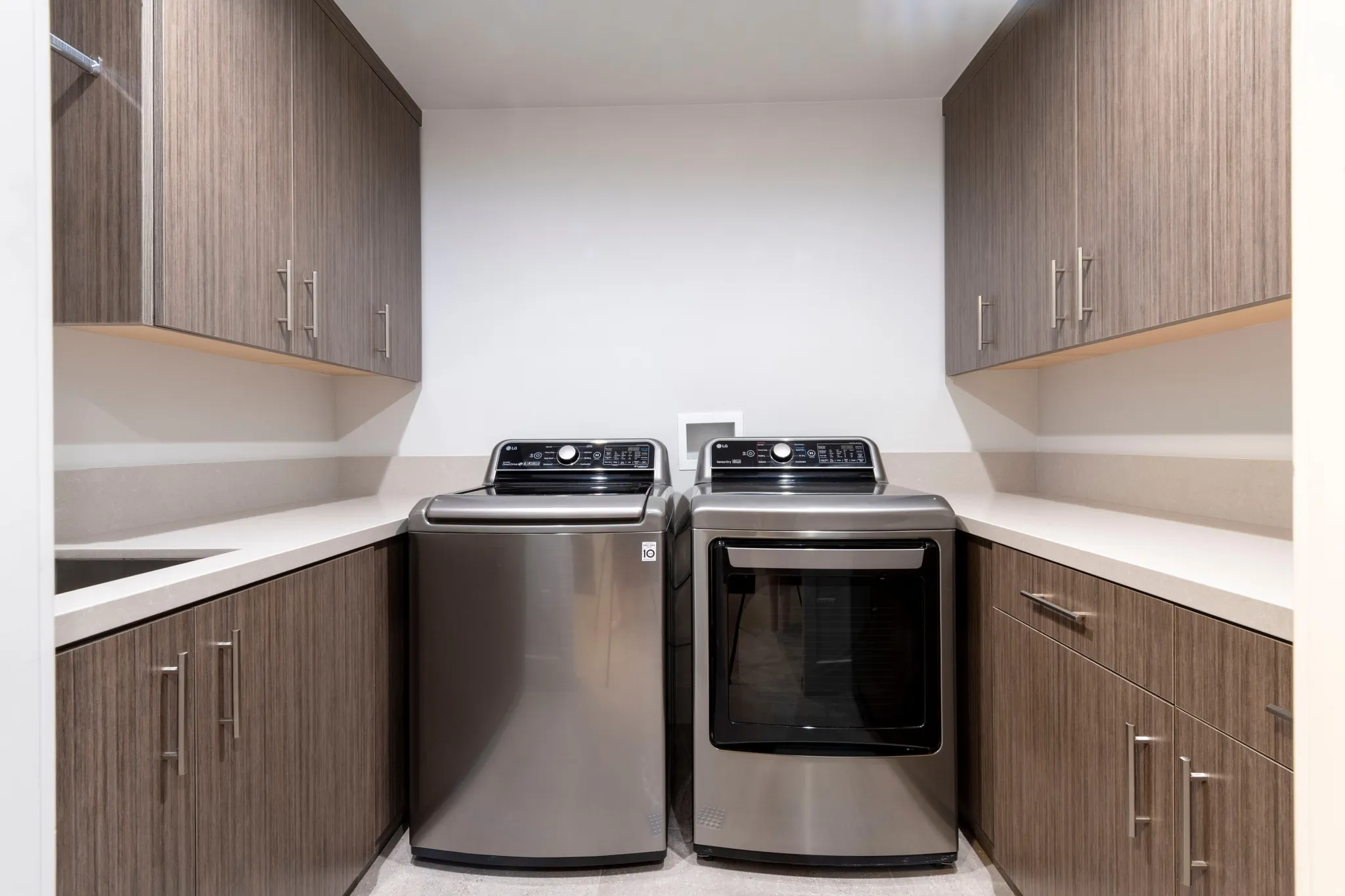 Integrated cabinetry with wood-finish doors, stainless steel hardware, light-toned countertops, and a built-in sink