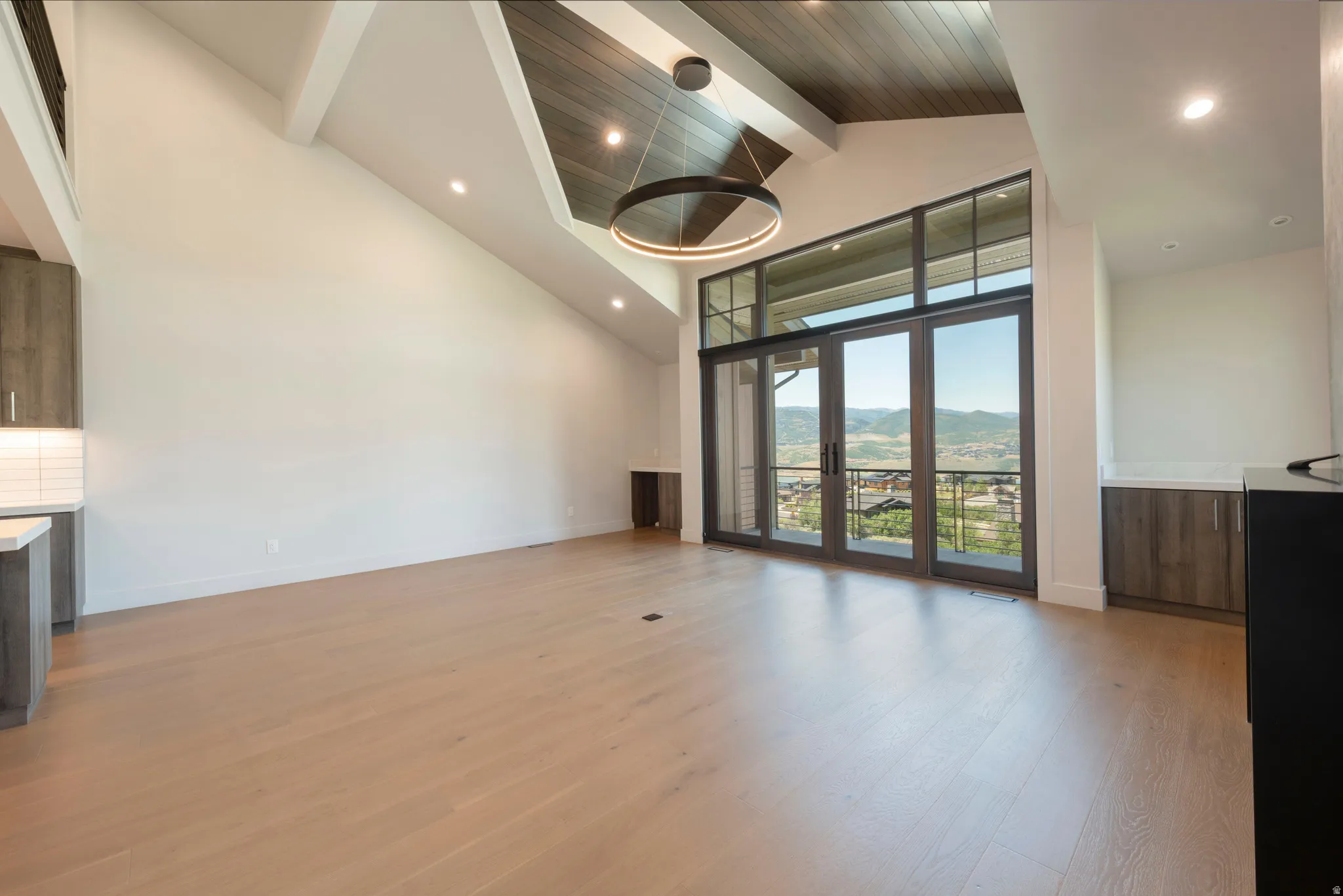 Vaulted ceiling with wood-finish accents, large glass doors to an outdoor area, wood-finish flooring, recessed lighting, and a modern circular chandelier