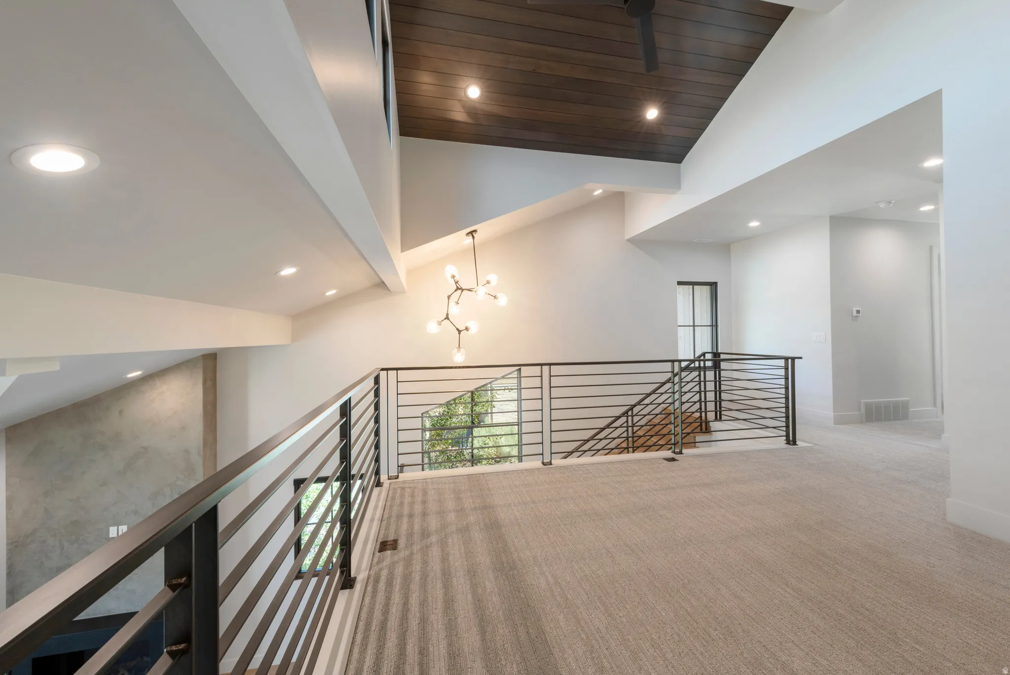 Vaulted ceilings with recessed lighting, dark wood-finish ceiling, modern chandelier, and horizontal bar railings
