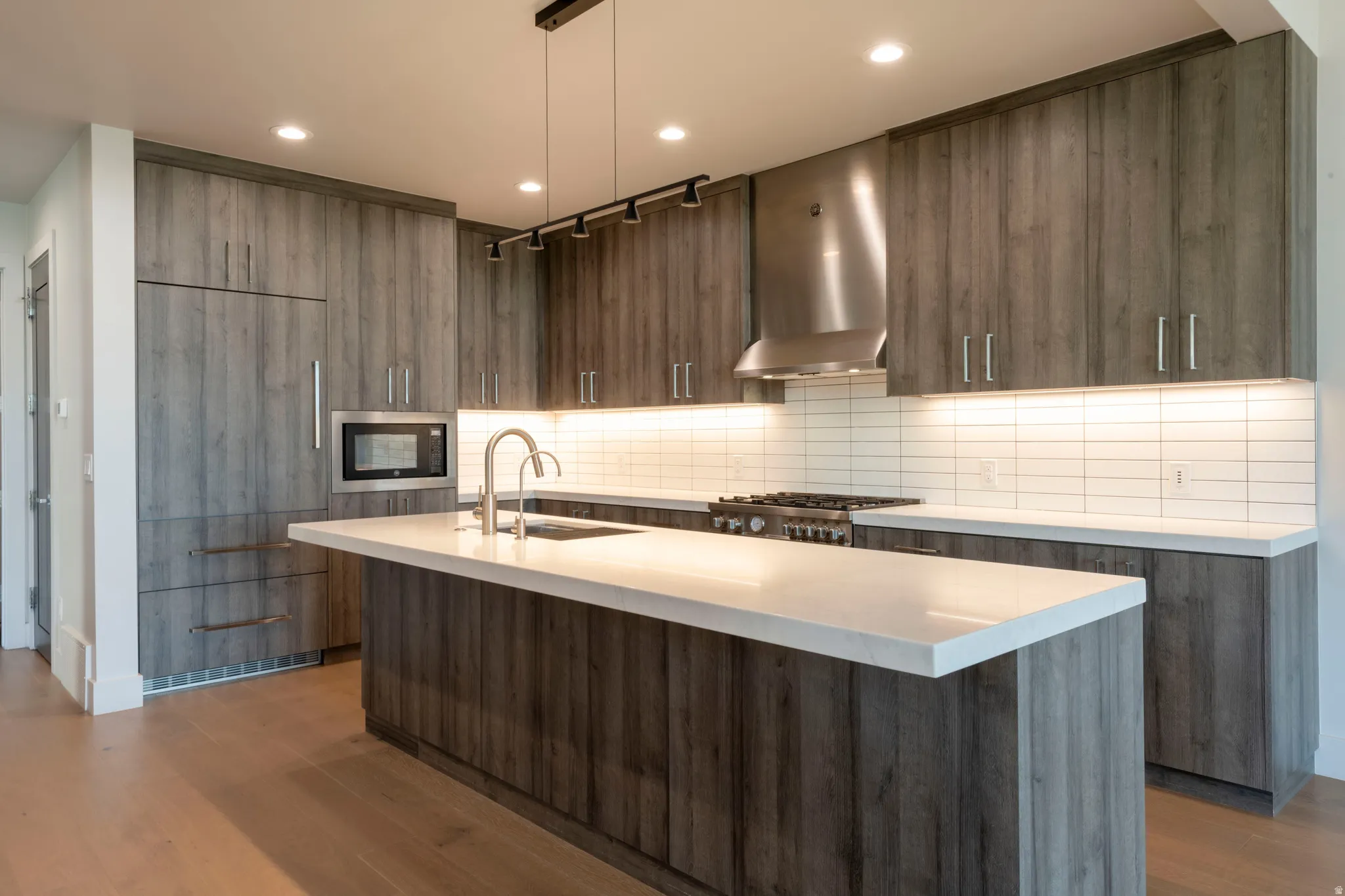 Modern kitchen with wood-finish cabinetry, a central island, recessed lighting, and a subway tile backsplash