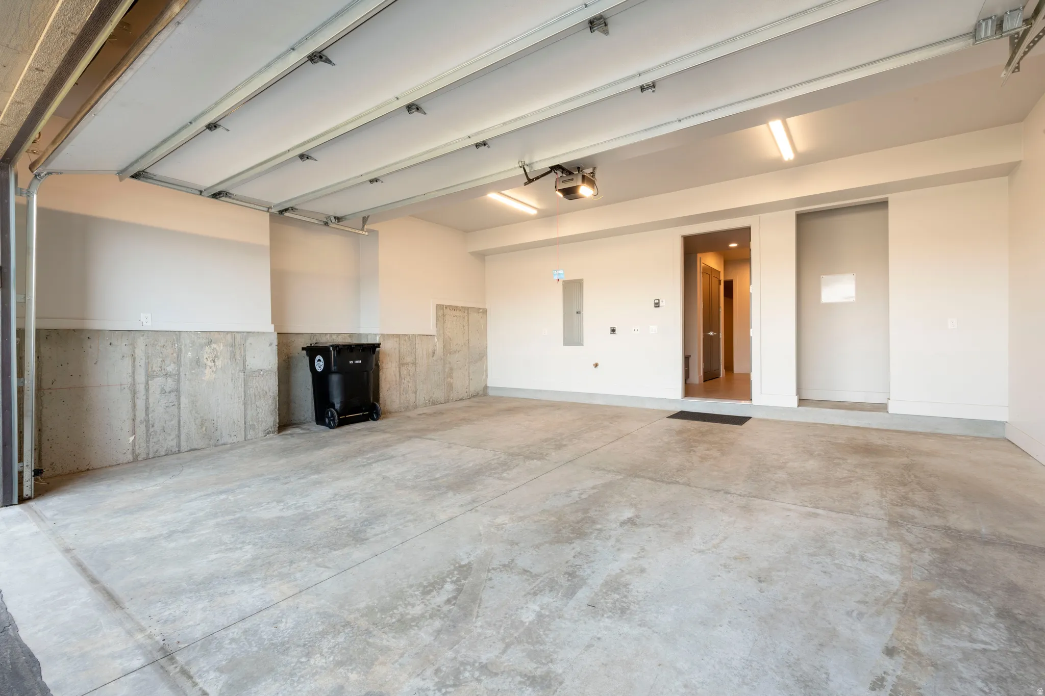 Spacious garage with concrete flooring, automatic garage door opener, overhead fluorescent lighting, and direct interior access