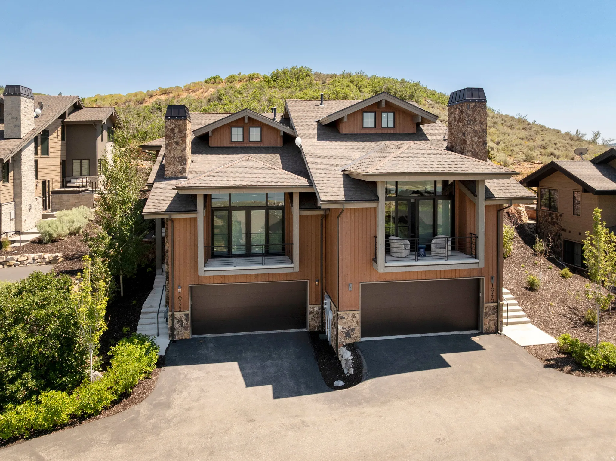 Modern exterior with wood-finish siding, stone accents, and a covered balcony