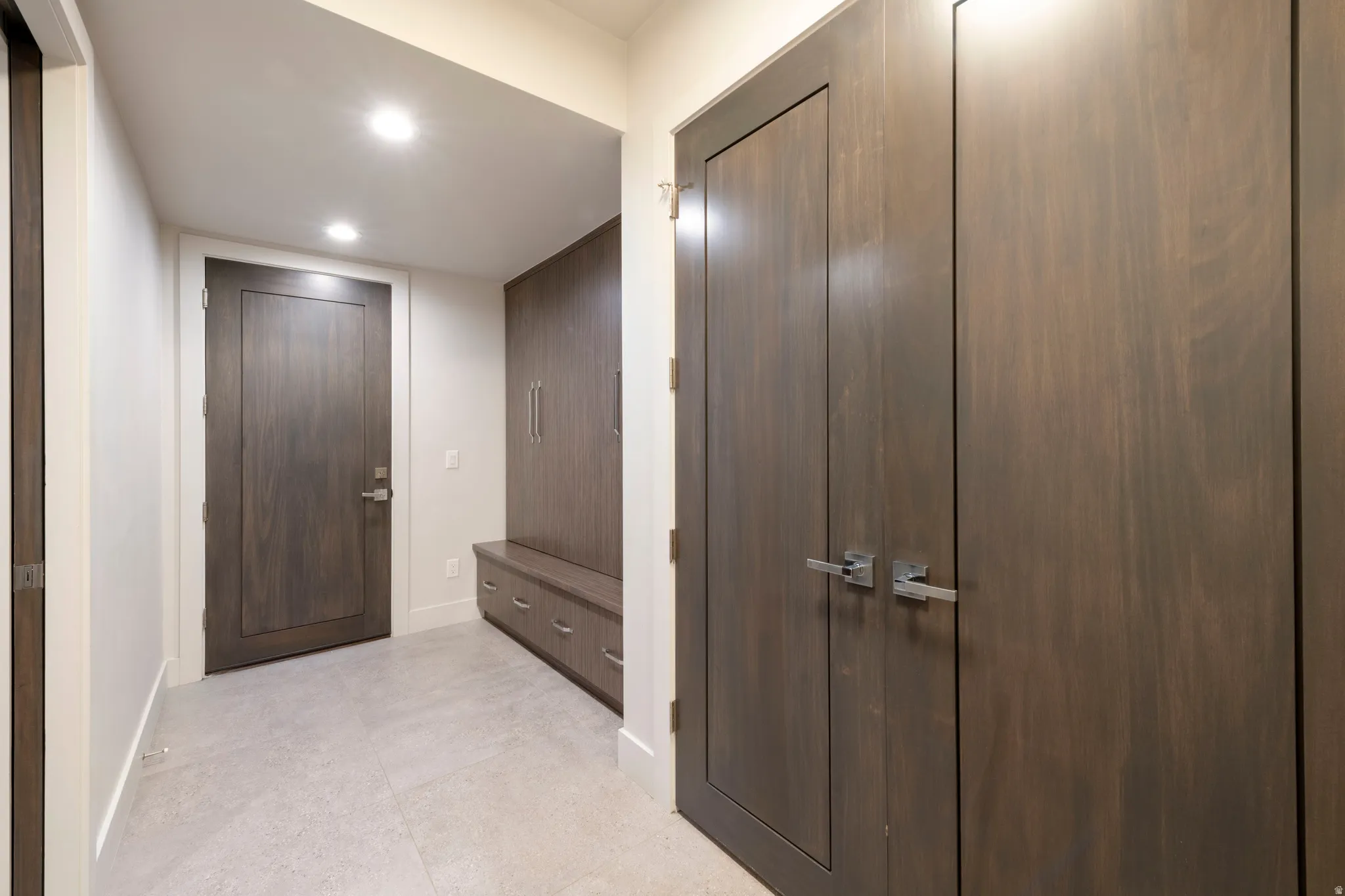 Built-in storage solutions, wood-finish doors, recessed lighting, and light-toned flooring