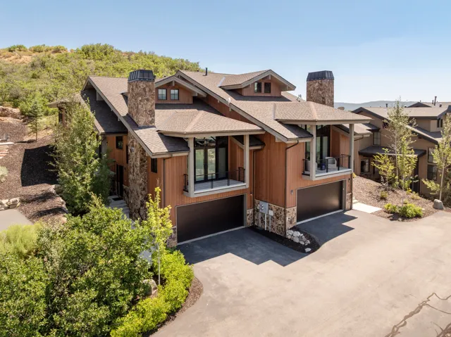 Multi-level architectural design featuring stacked stone accents, wood-paneled siding, and multiple balconies