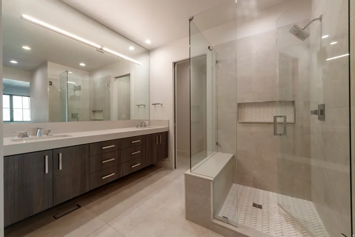 Dual vanity with undermount sinks, wood-finish cabinetry, and a large mirror