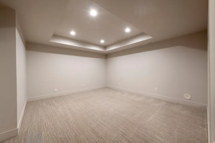 Recessed tray ceiling with integrated lighting, neutral wall finishes, wide baseboards, and textured carpeting