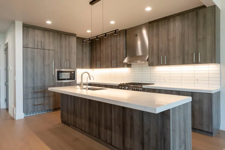 Modern kitchen with wood-finish cabinetry, a central island, recessed lighting, and a subway tile backsplash
