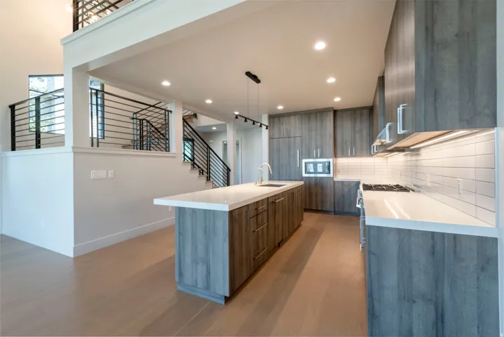 Contemporary kitchen featuring wood-finish cabinetry, white countertops, stainless steel appliances, and a tile backsplash