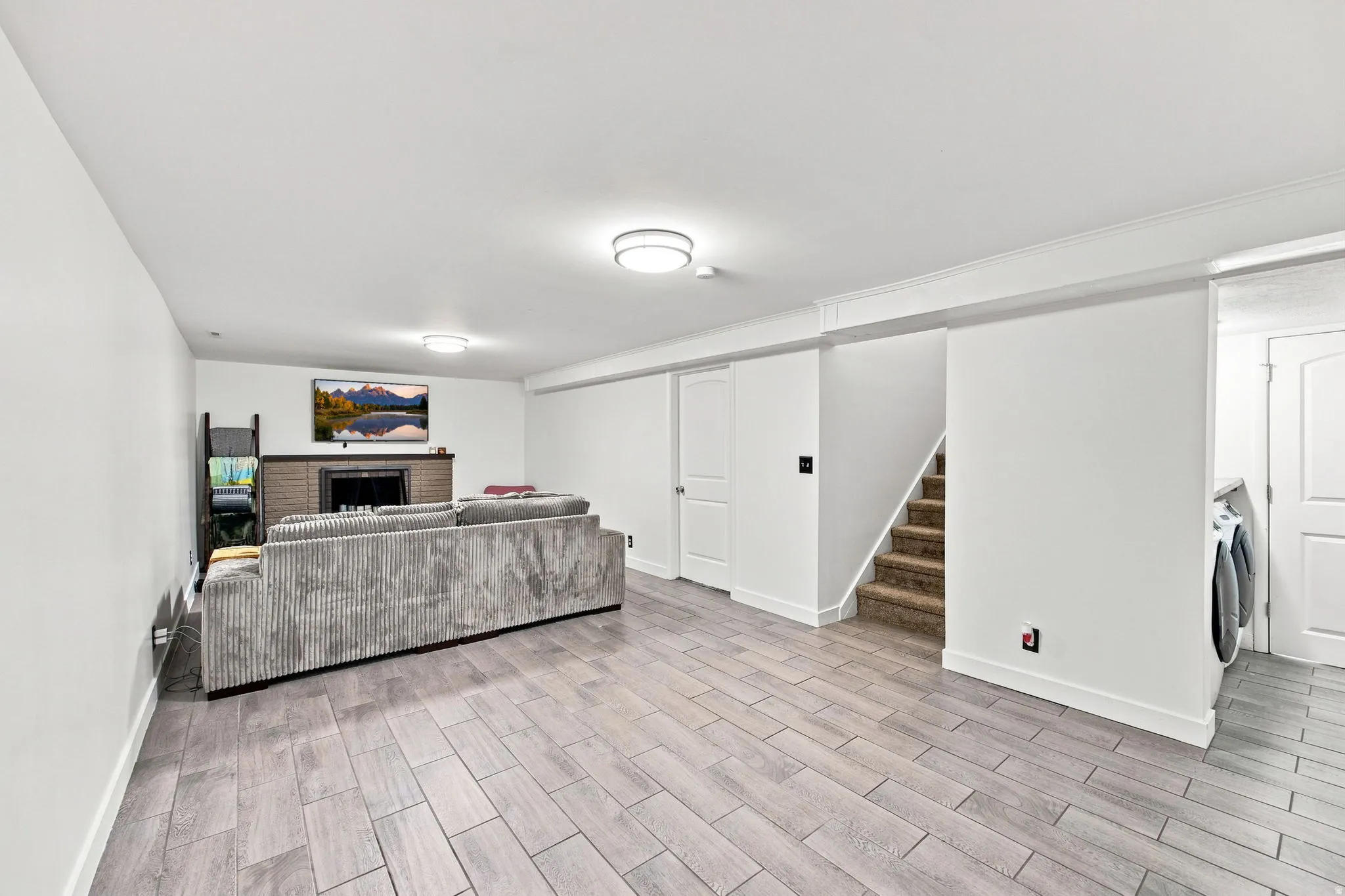 White-painted interior with crown molding, recessed lighting, wood-finish flooring, and a brick-surround fireplace