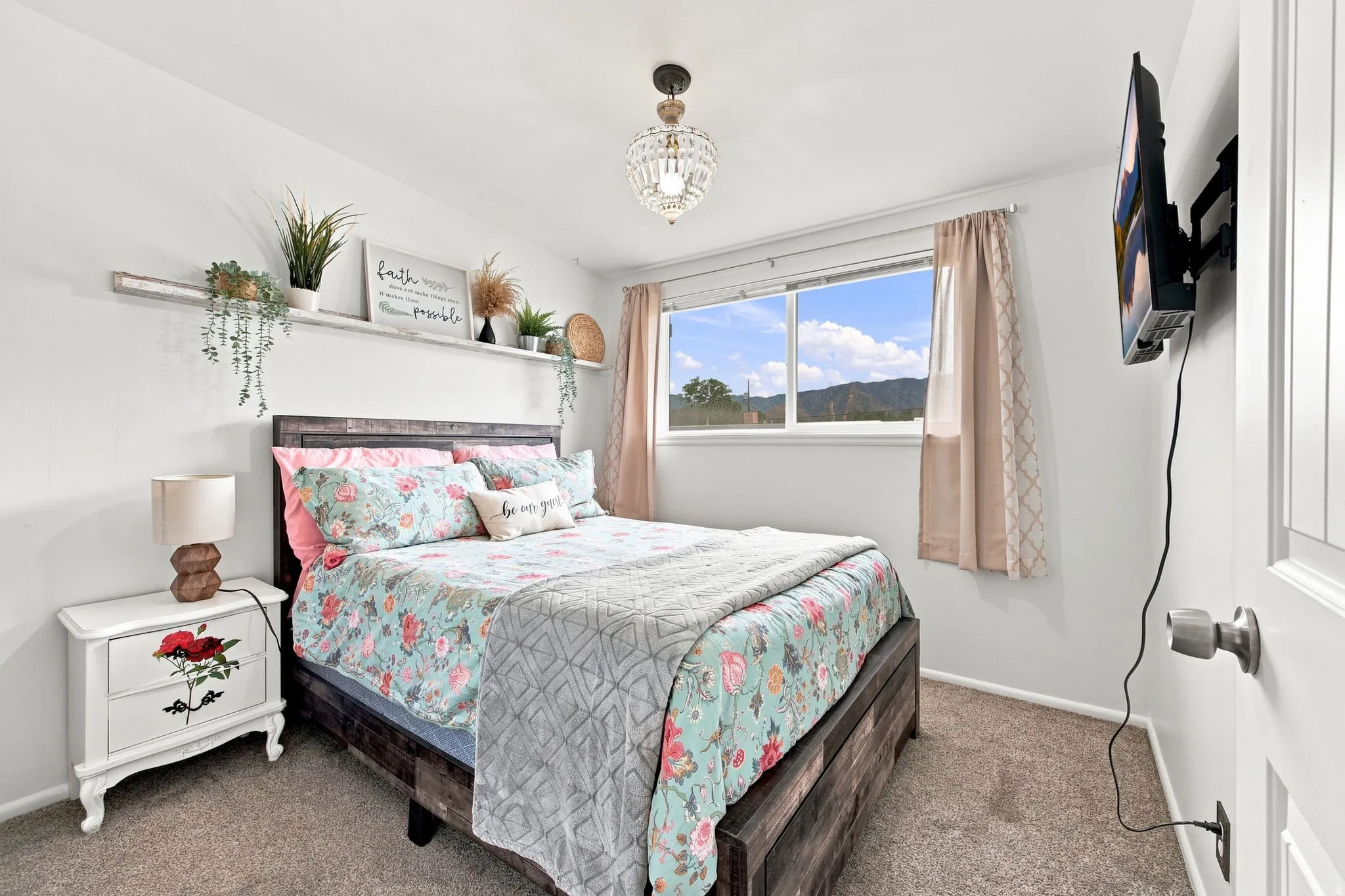 Built-in floating wall shelf, window with exterior scenery, crystal chandelier, wall-mounted television, and carpeted flooring