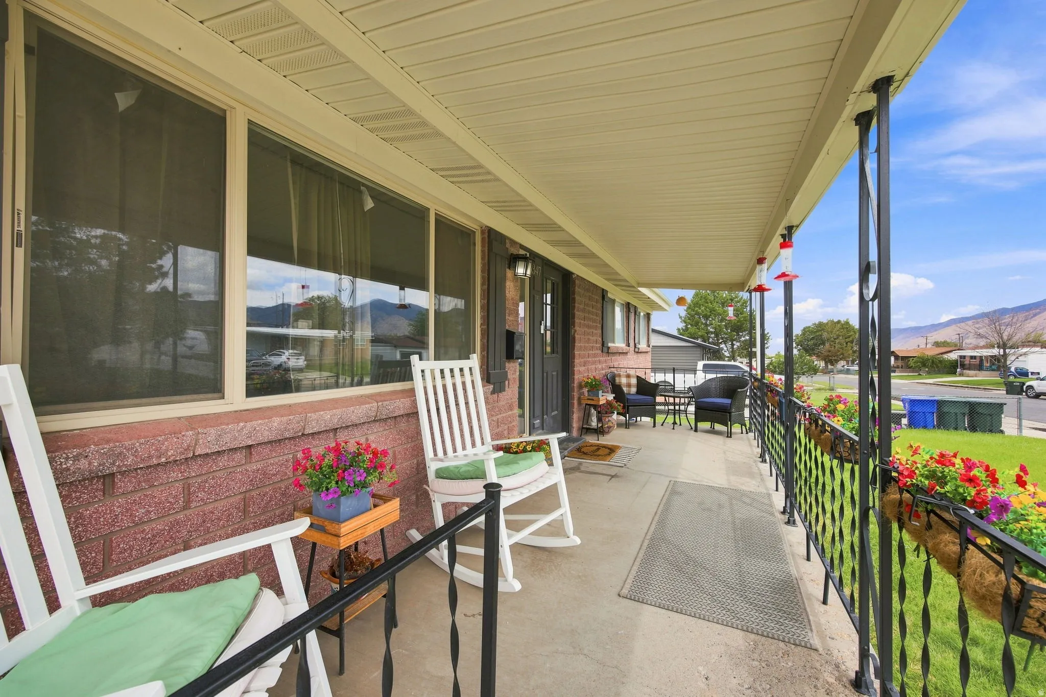 Covered front porch featuring brick siding, a concrete surface, and decorative metal railings