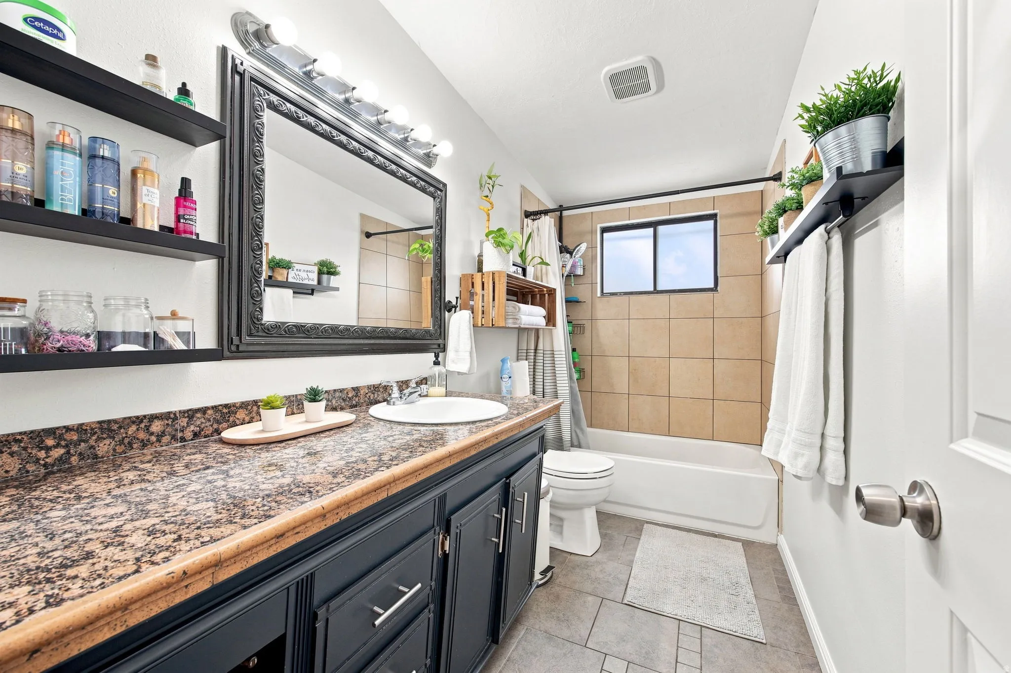 Bathroom featuring a dark wood vanity with a granite-style countertop, a framed mirror, and a white porcelain sink